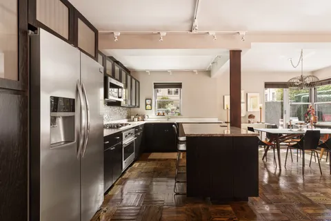 a kitchen with granite countertop a refrigerator a stove a sink a dining table and chairs with wooden floor