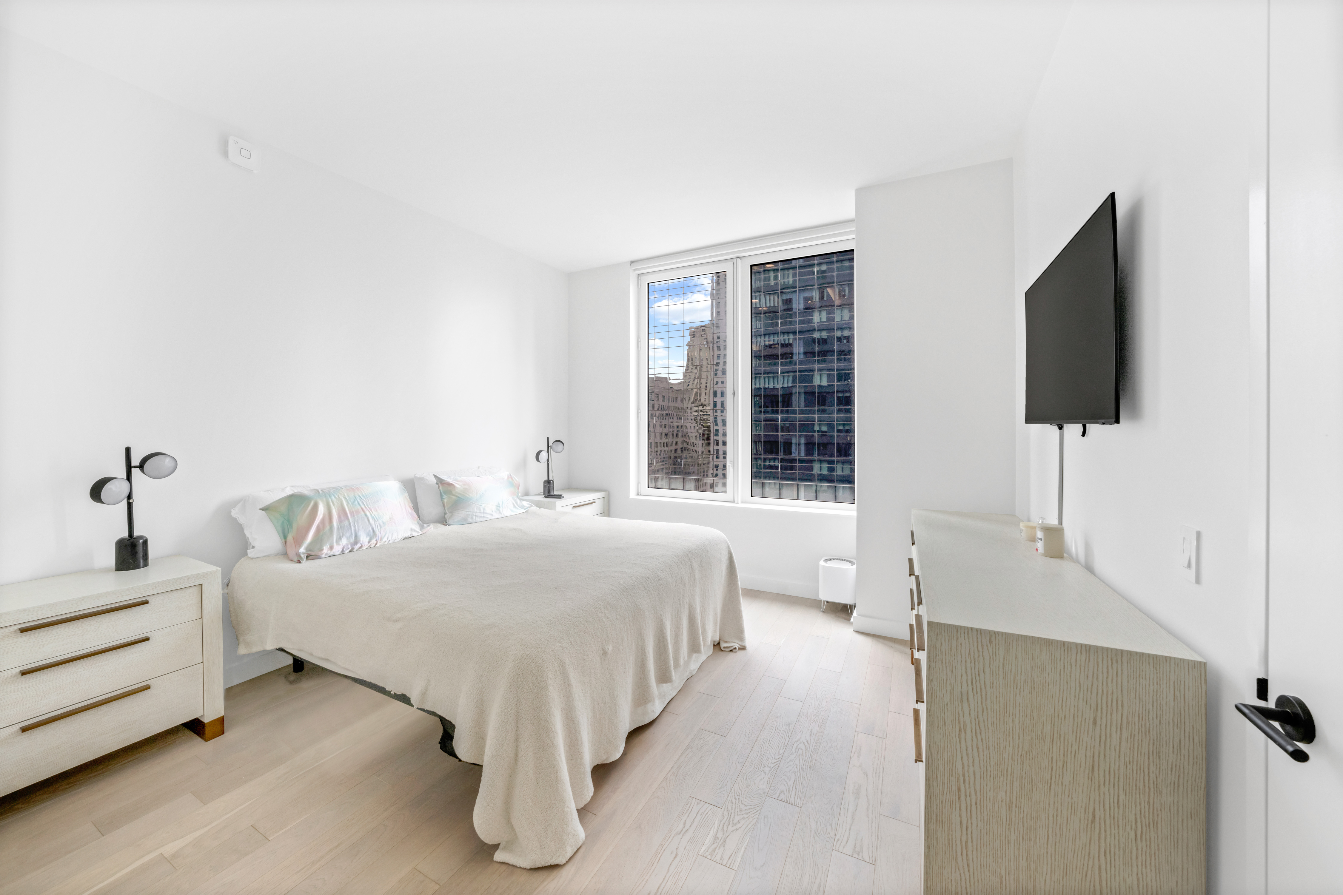 1 West 60th Street, Unit 16C Manhattan, NY 10019 - Photo 3 of 8 a bedroom with a bed and a flat screen tv