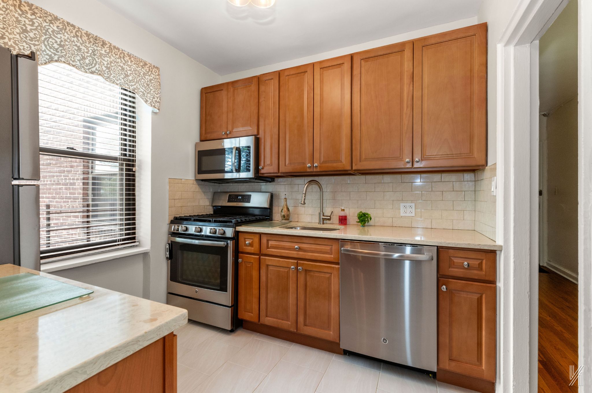 22-08 76th Street, Unit D2 Queens, NY 11370 - Photo 10 of 20 a kitchen with stainless steel appliances granite countertop a stove a sink and a microwave