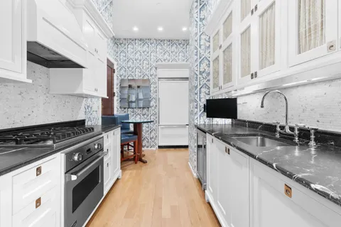 a kitchen with stainless steel appliances granite countertop a sink a stove and a wooden floors