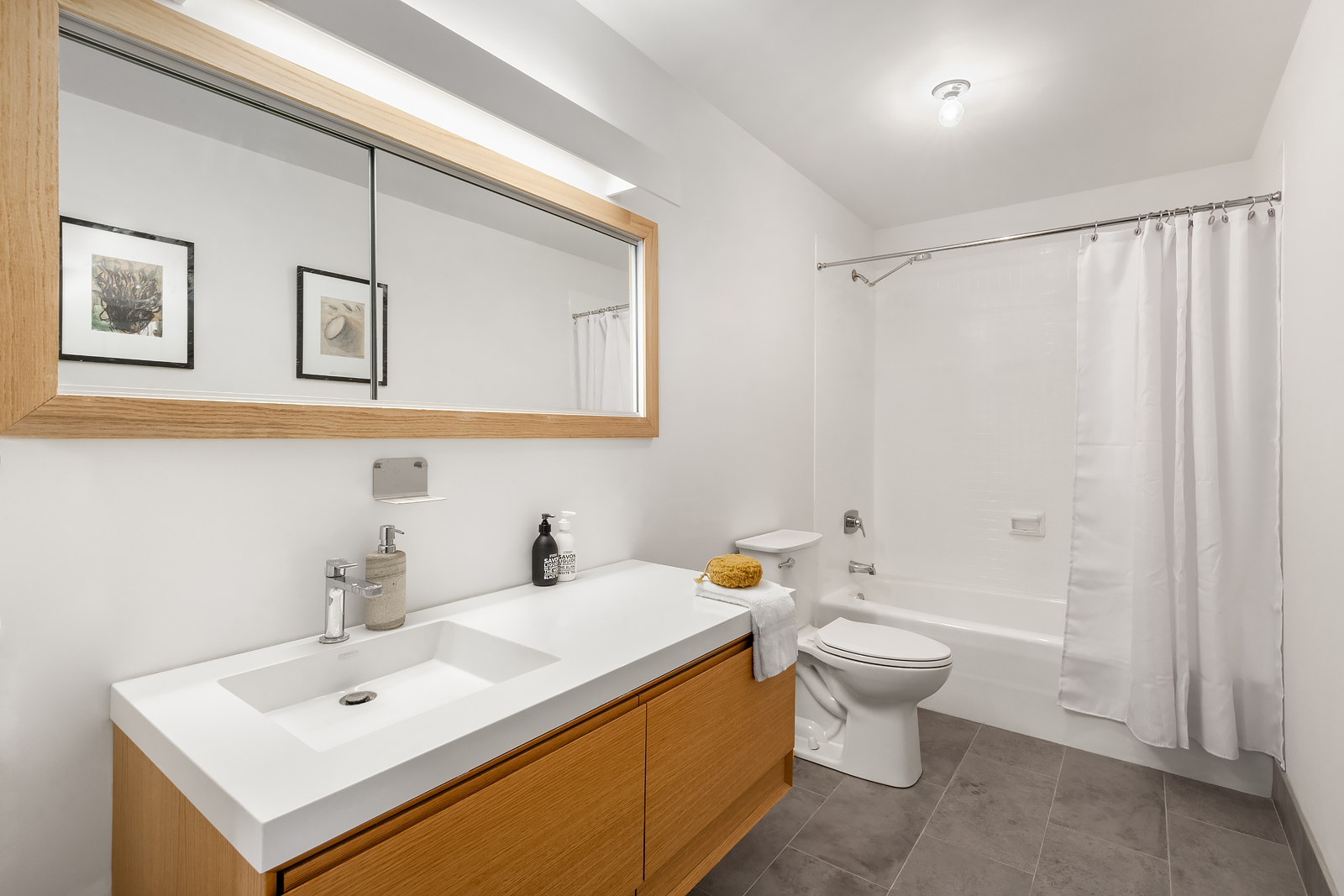 448 West 37th Street, Unit 12F Manhattan, NY 10018 - Photo 8 of 11 a bathroom with a sink a toilet and shower curtain