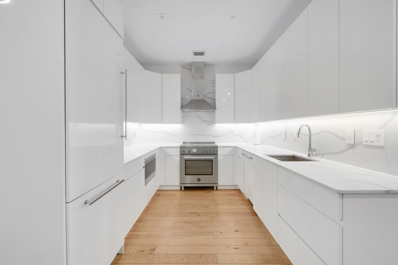 100 2nd Avenue, Unit 2 Manhattan, NY 10003 - Photo 3 of 10 a large white kitchen with granite countertop a sink and dishwasher a stove top oven with wooden floor