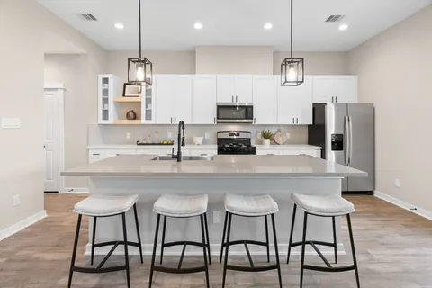 a kitchen with stainless steel appliances a dining table chairs refrigerator and microwave