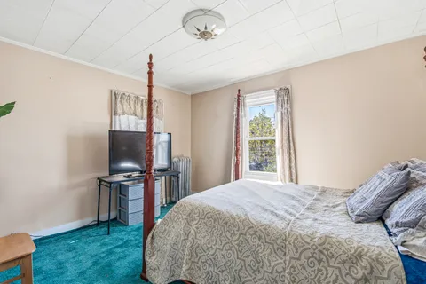 a bedroom with a bed table and flat screen tv