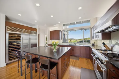 a kitchen with stainless steel appliances granite countertop table chairs stove and refrigerator