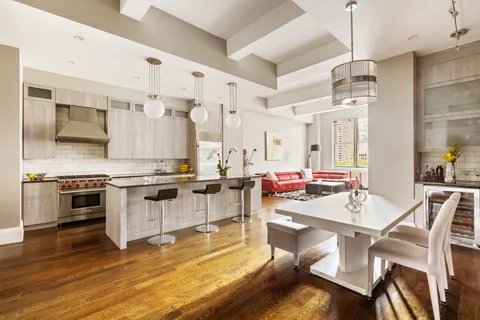 a kitchen with stainless steel appliances a stove a sink dishwasher and white cabinets with wooden floor