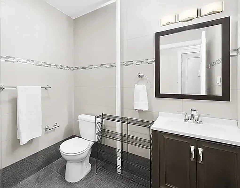 1436 Lexington Avenue, Unit 1B Manhattan, NY 10128 - Photo 3 of 4 a bathroom with a toilet sink and mirror