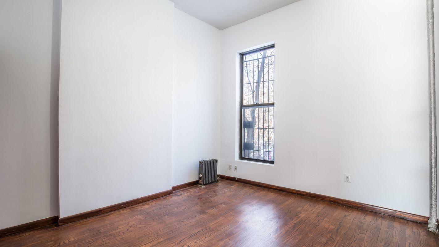 27 Brevoort Place, Unit 2 Brooklyn, NY 11216 - Photo 8 of 9 an empty room with wooden floor and windows
