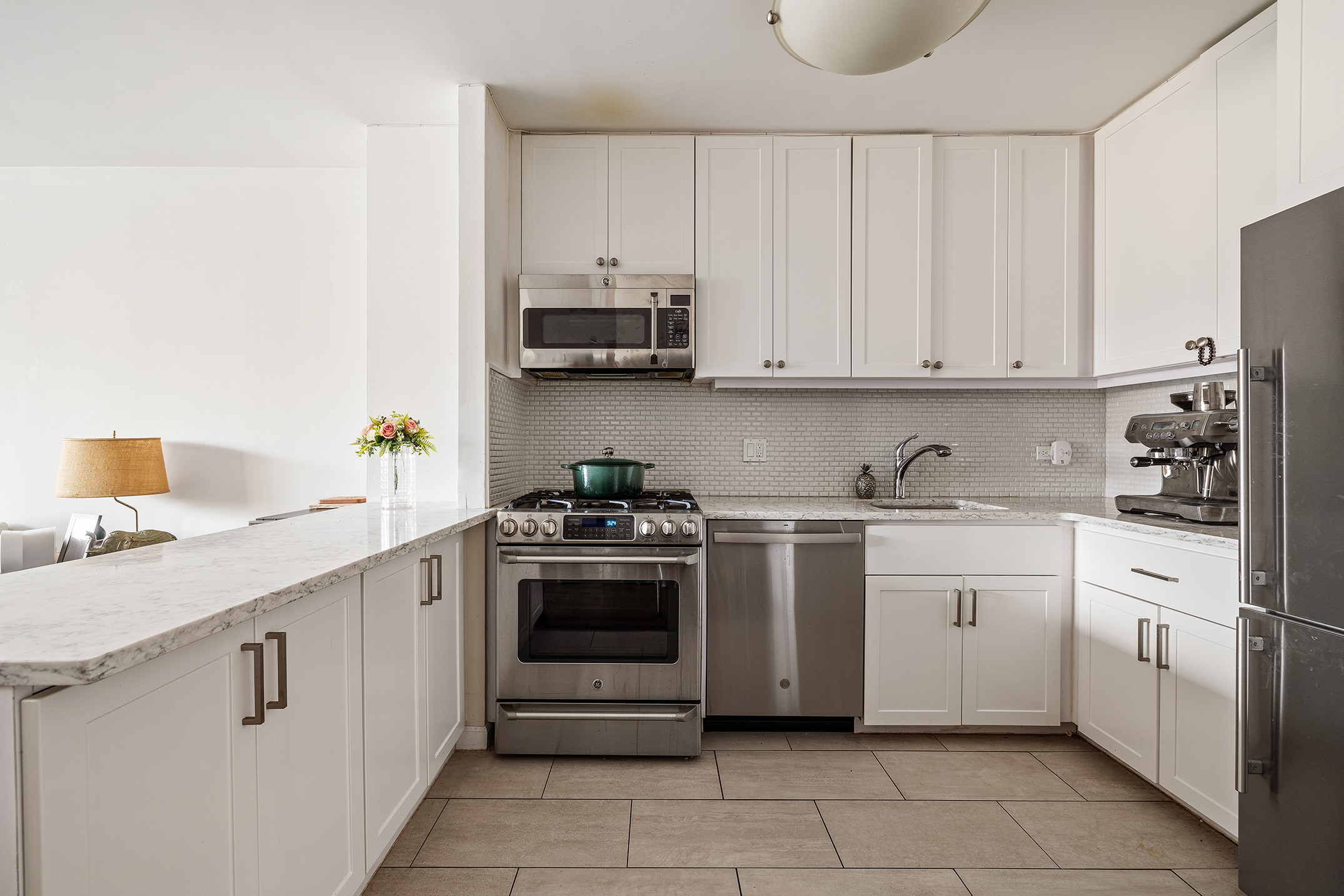 22 West 15th Street, Unit 10G Manhattan, NY 10011 - Photo 3 of 11 a kitchen with stainless steel appliances granite countertop a sink and dishwasher a stove top oven with white cabinets