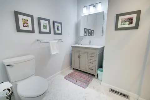 a view of a hallway with wooden floor and a bathroom