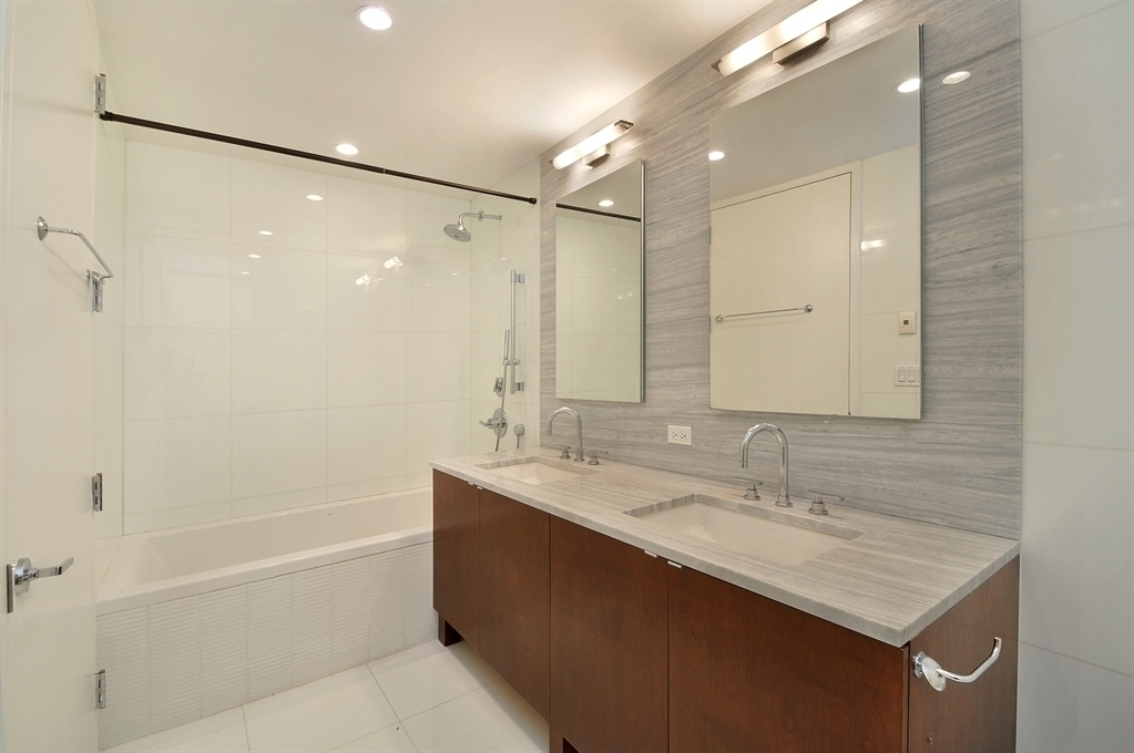 117 West 123rd Street, Unit 4B Manhattan, NY 10027 - Photo 8 of 16 a bathroom with a sink double vanity mirror and a bathtub