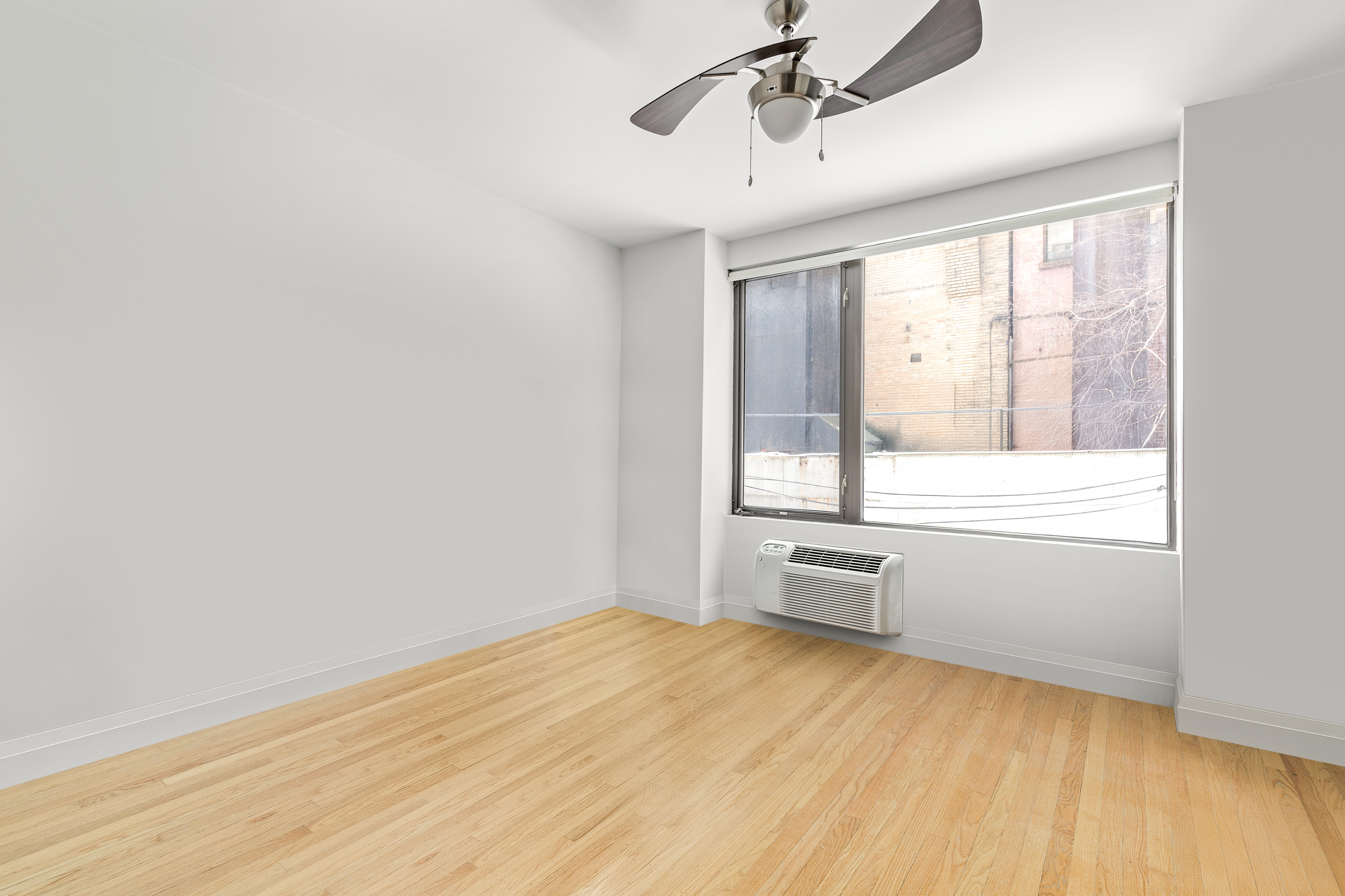 212 East 95th Street, Unit 2C Manhattan, NY 10128 - Photo 9 of 11 an empty room with wooden floor and windows