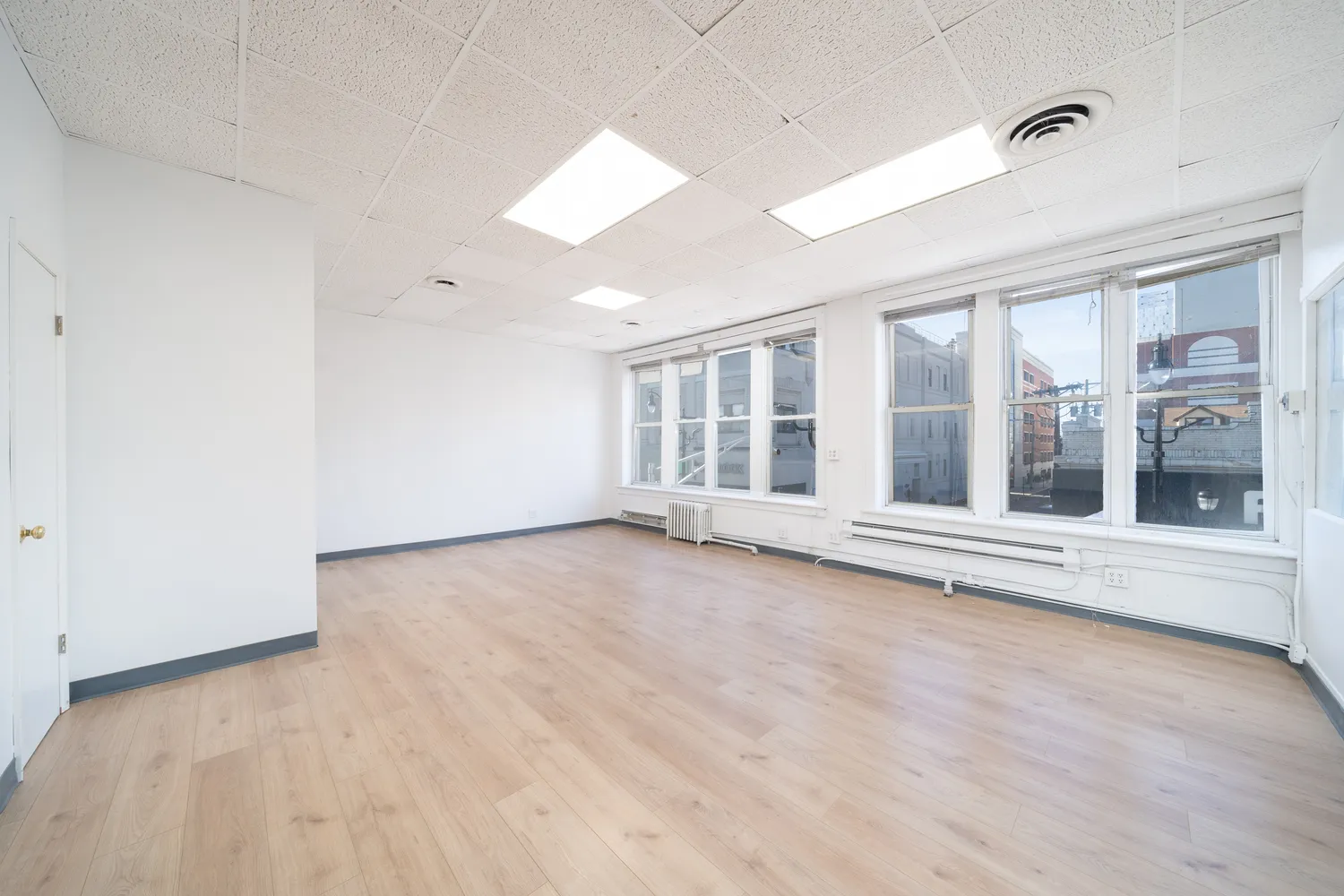 an empty room with wooden floor and windows
