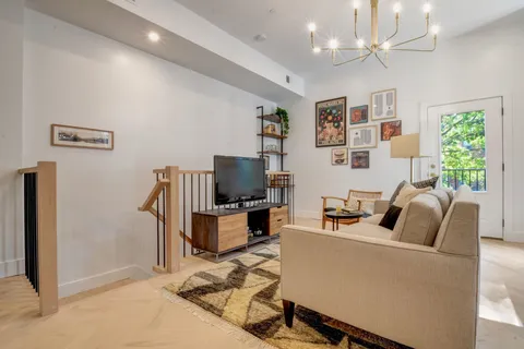 a living room with furniture a chandelier and a flat screen tv
