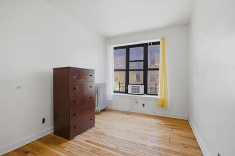 an empty room with wooden floor cabinet and windows