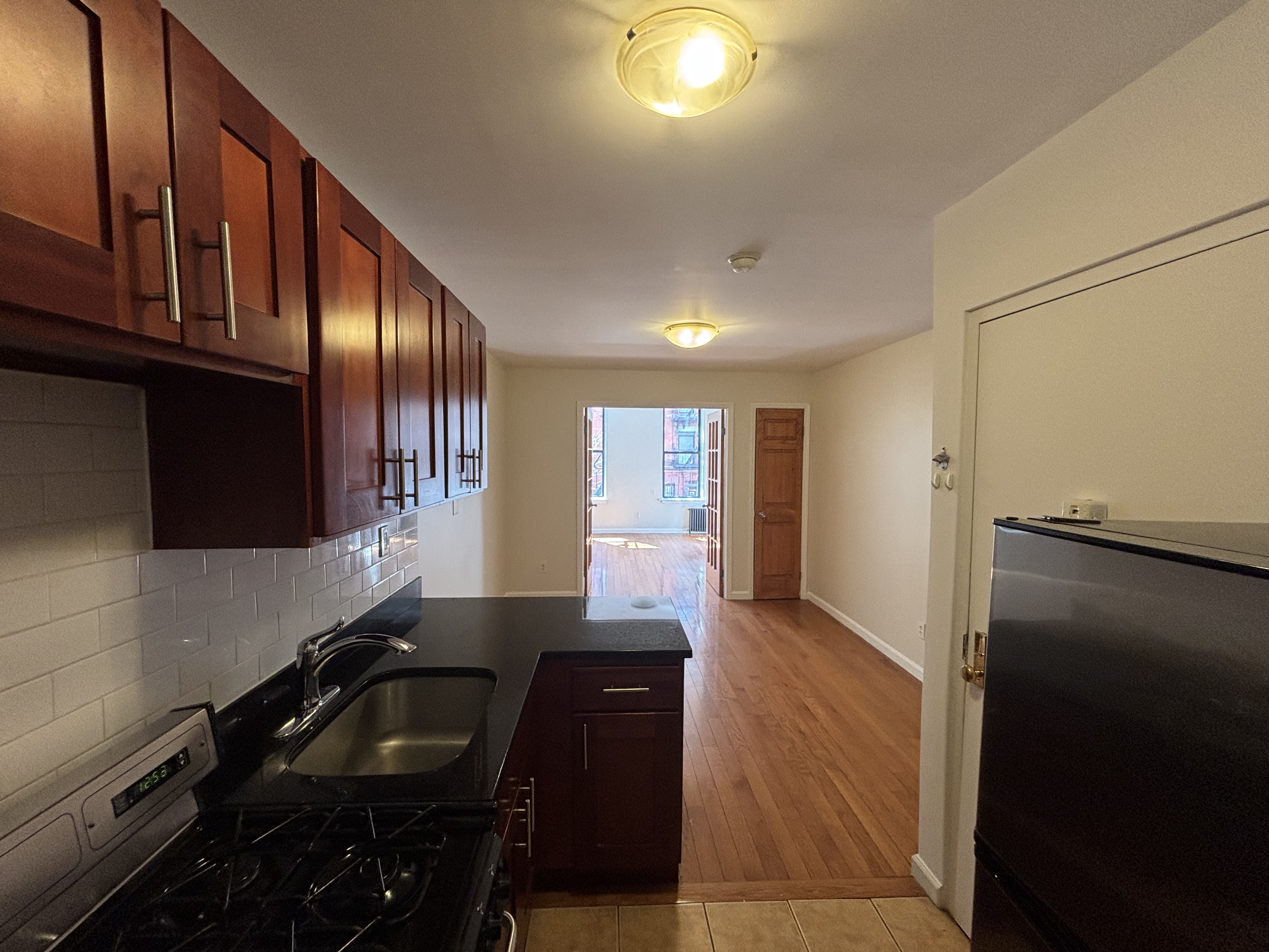 99 St Marks Place, Unit 4B Manhattan, NY 10009 - Photo 5 of 10 a kitchen with granite countertop stove top oven microwave and cabinets