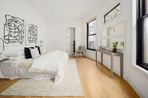 a spacious bedroom with a bed and a large mirror on the dresser