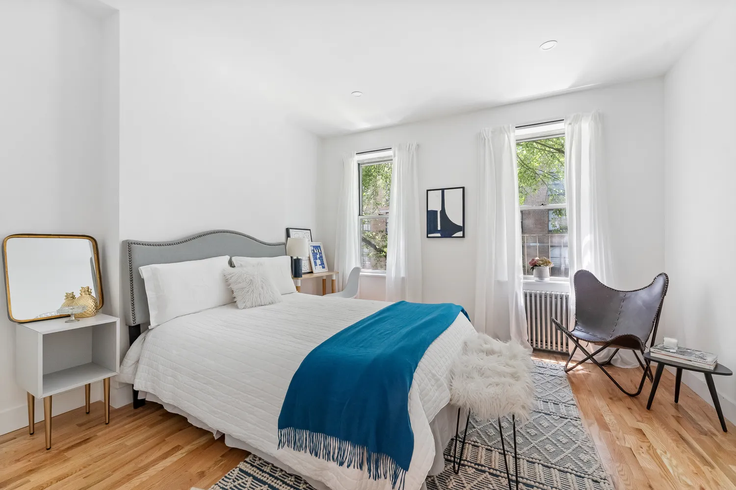 a bedroom with a bed a chair and windows