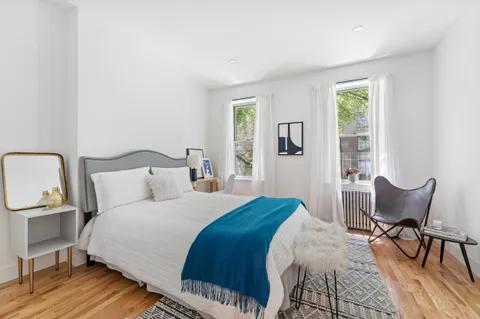 a bedroom with a bed a chair and windows