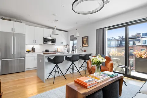 a kitchen with stainless steel appliances granite countertop a stove top oven a sink dishwasher a dining table and chairs with wooden floor