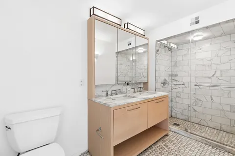 a bathroom with a granite countertop sink a toilet and shower
