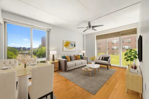 a living room with furniture large windows a rug and a chandelier