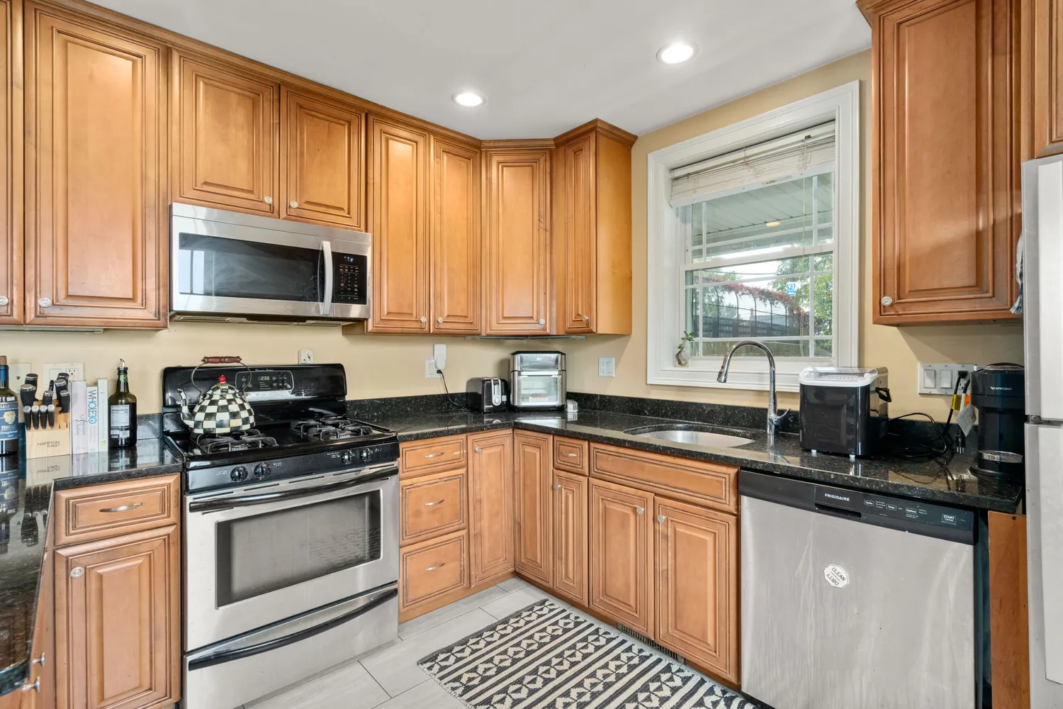 a kitchen with granite countertop a stove top oven microwave and cabinets