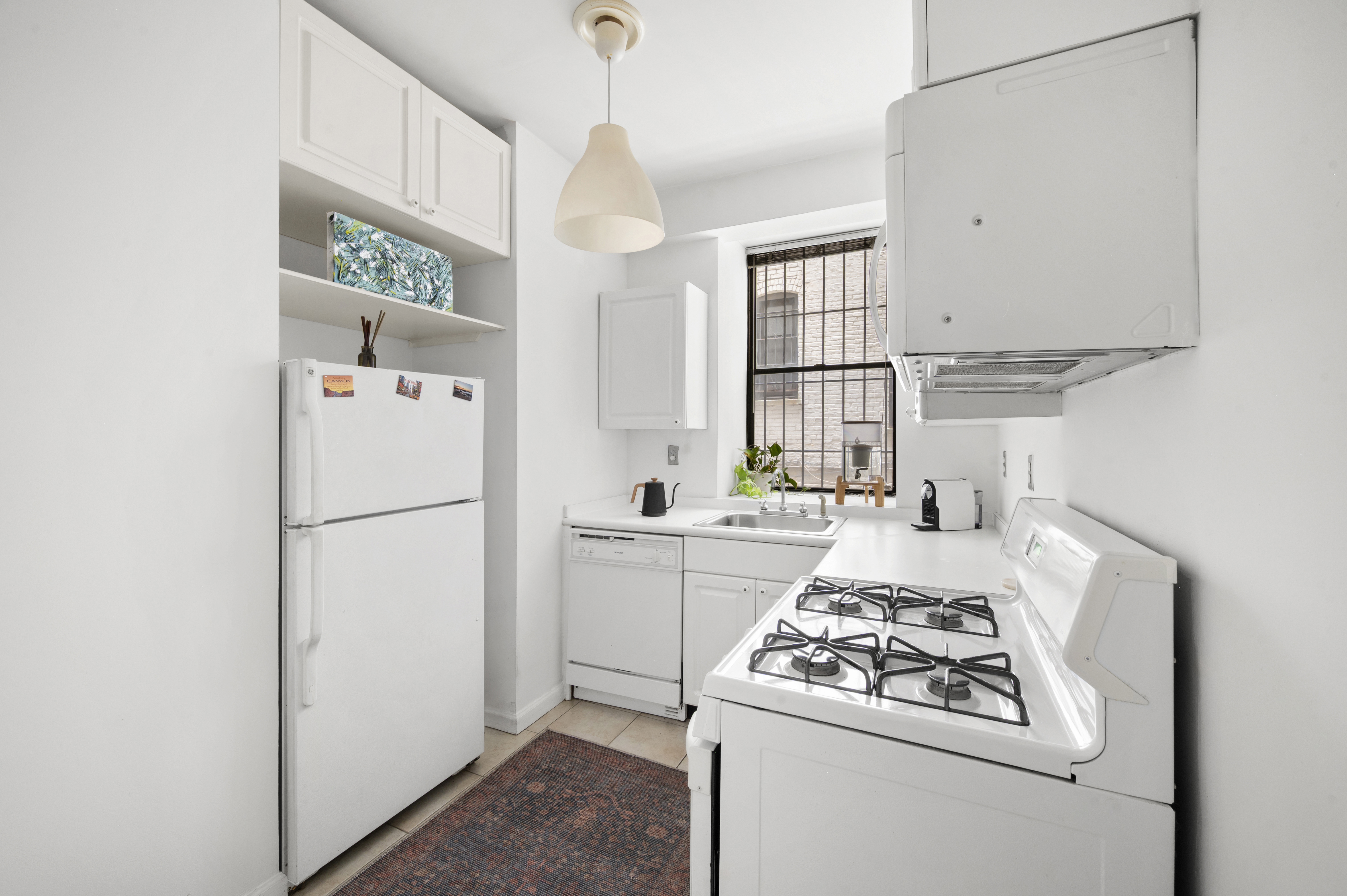 251 West 98th Street, Unit DD Manhattan, NY 10025 - Photo 3 of 6 a kitchen with stainless steel appliances granite countertop a refrigerator stove sink and a window