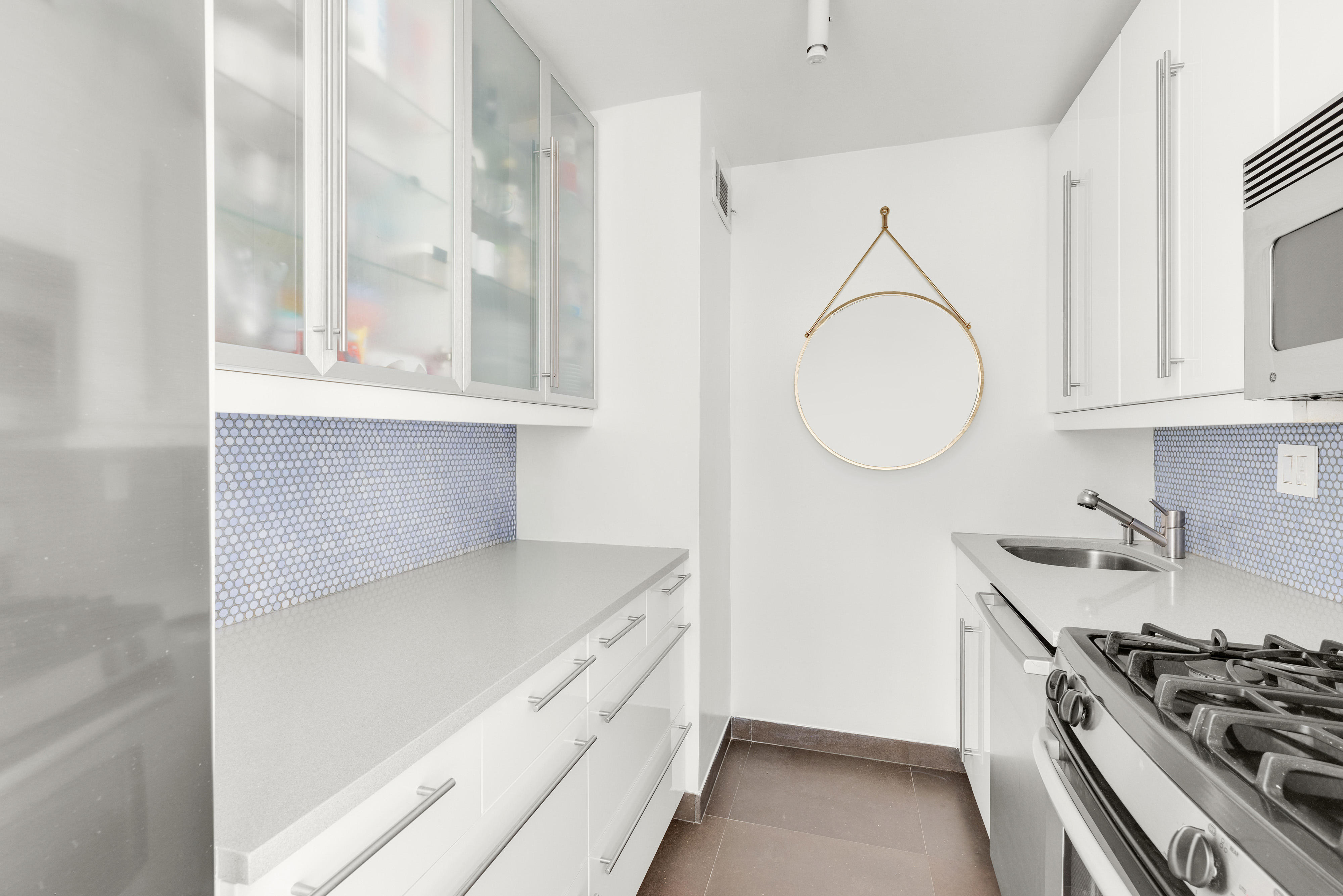 201 East 17th Street, Unit 31E Manhattan, NY 10003 - Photo 3 of 15 a kitchen with stainless steel appliances a stove and a white cabinet with granite countertops