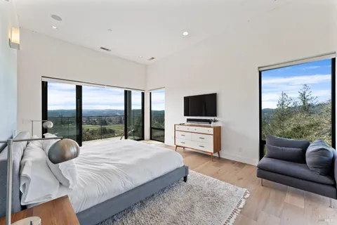 a bedroom with a bed and large windows