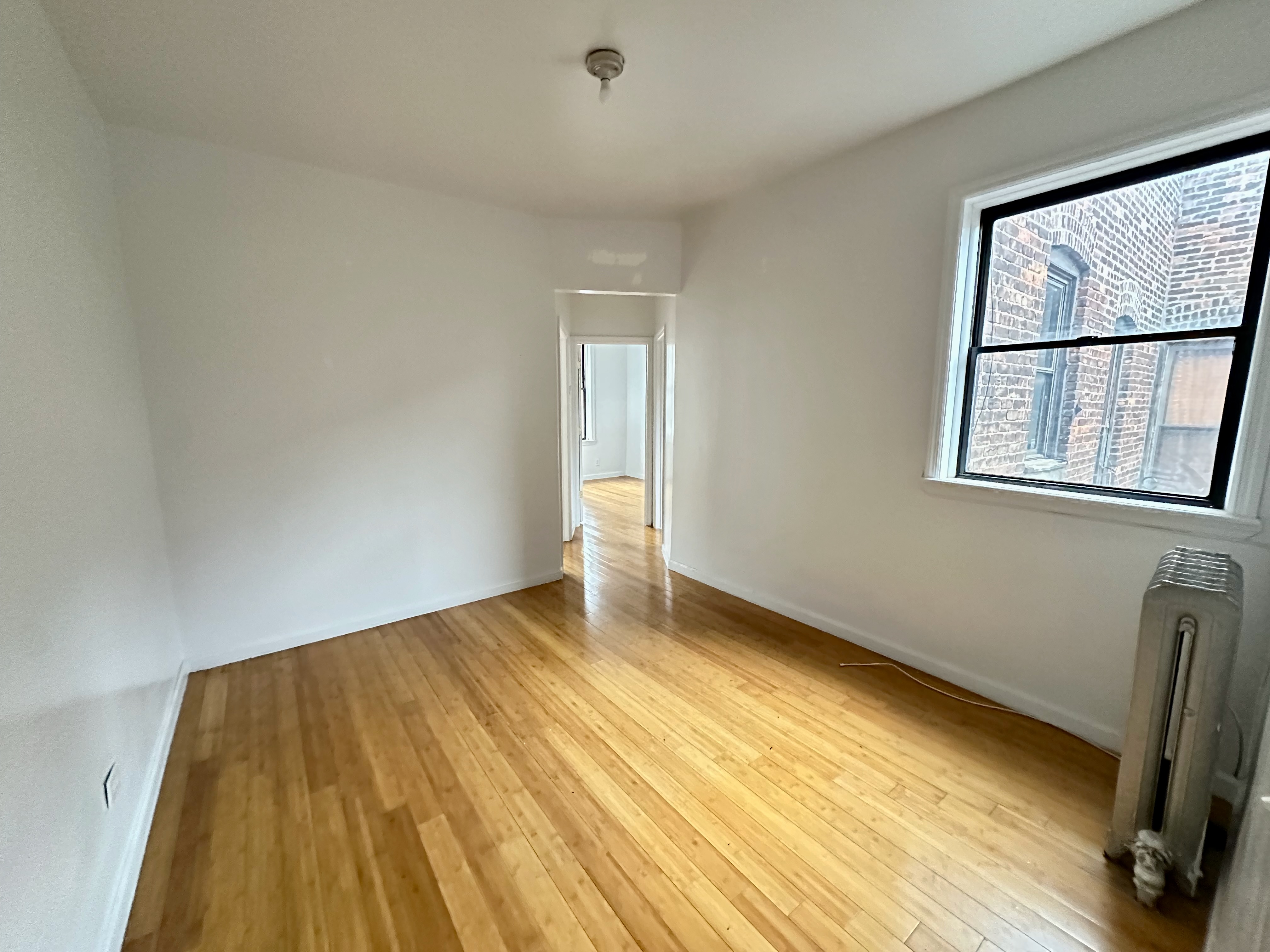 541 West 144th Street, Unit 17 Manhattan, NY 10031 - Photo 2 of 6 an empty room with wooden floor and windows