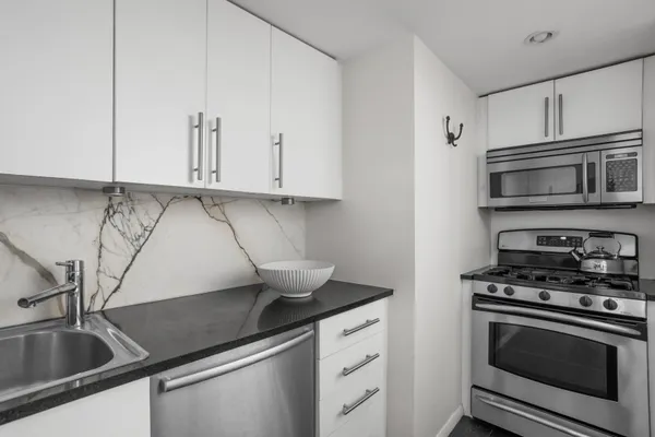 a kitchen with stainless steel appliances granite countertop a sink a stove and cabinets