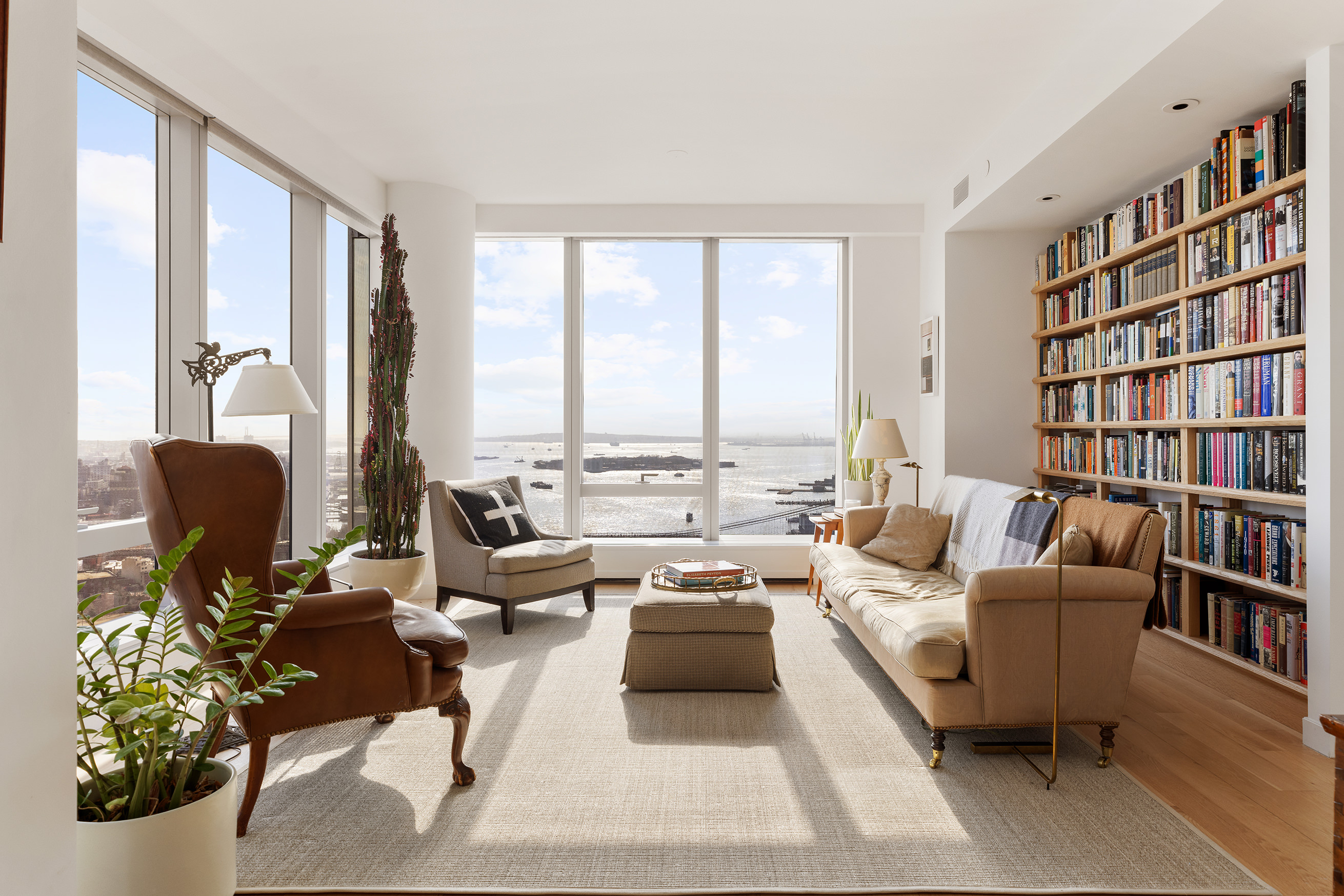 a living room with furniture bookshelf and a large window