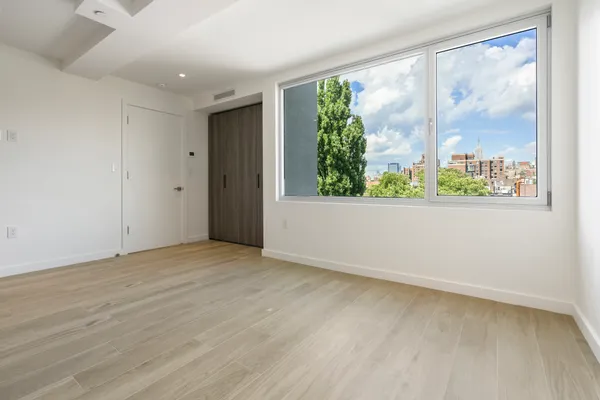 a view of an empty room with wooden floor and a window