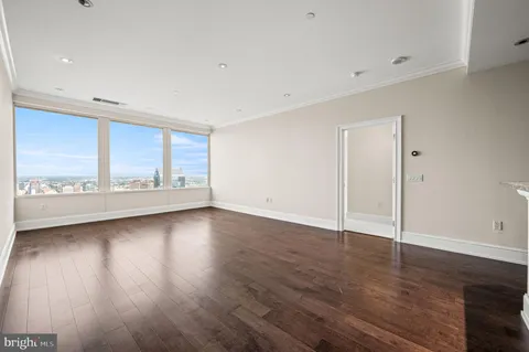 an empty room with wooden floor and windows