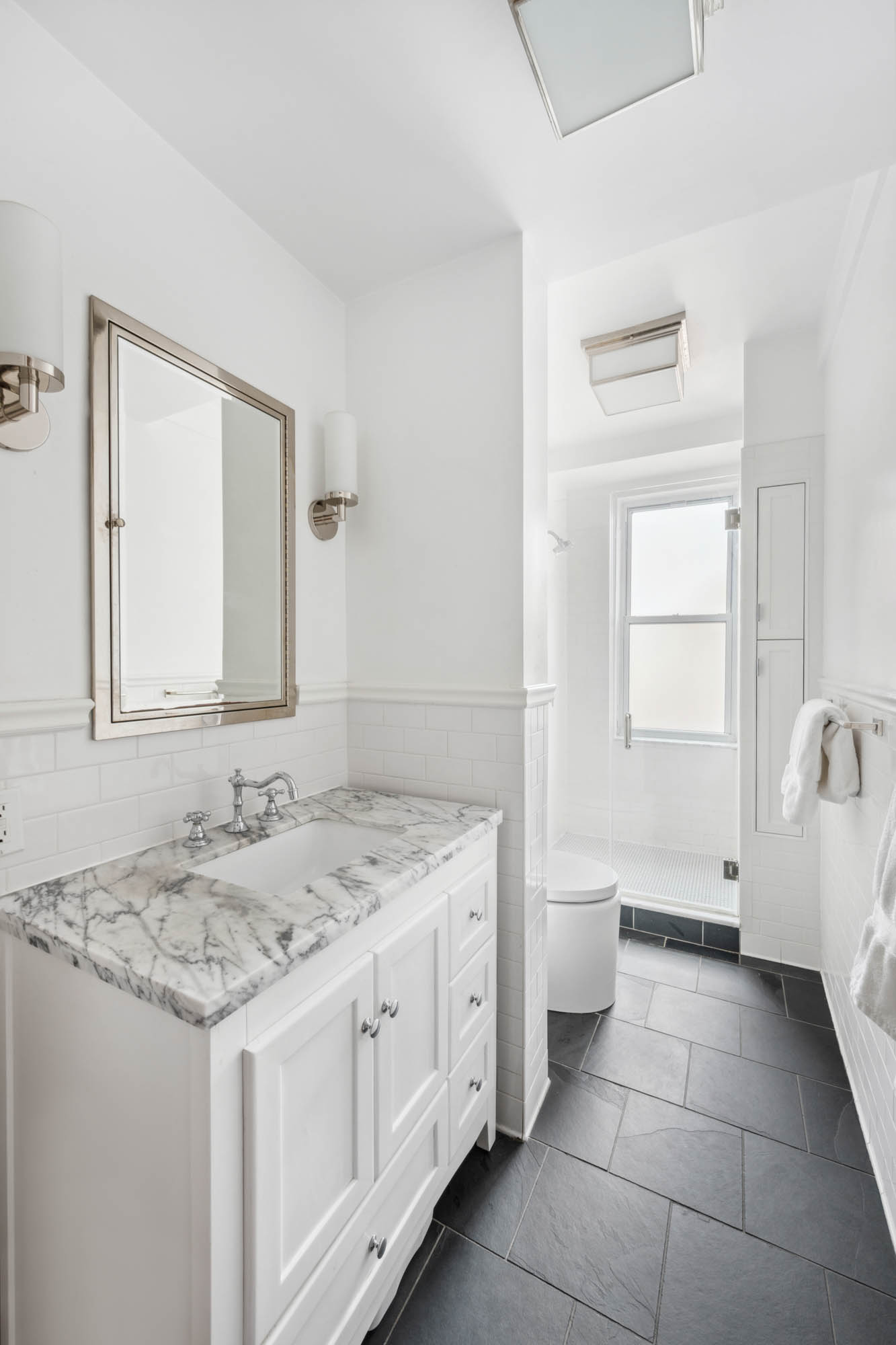 136 East 36th Street, Unit 9/10C Manhattan, NY 10016 - Photo 13 of 23 a spacious bathroom with a granite countertop sink a toilet and a mirror
