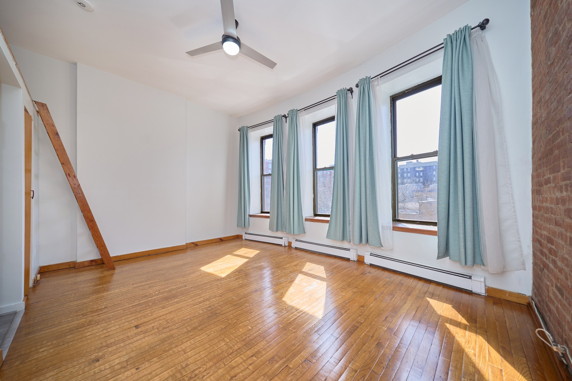 357 West 120th Street, Unit 2F Manhattan, NY 10027 - Photo 2 of 8 a view of an empty room with wooden floor and a window