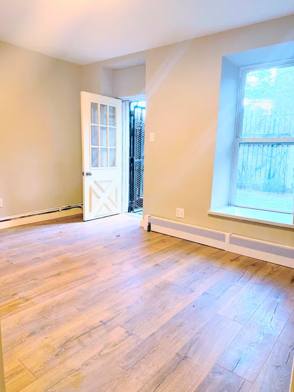 a view of an empty room with wooden floor and a window