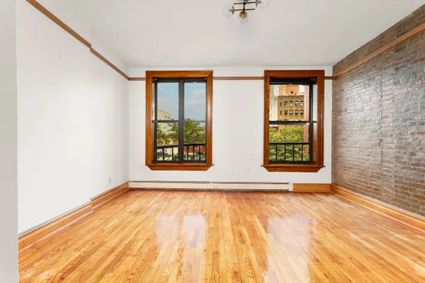 a view of an empty room with a window and wooden floor