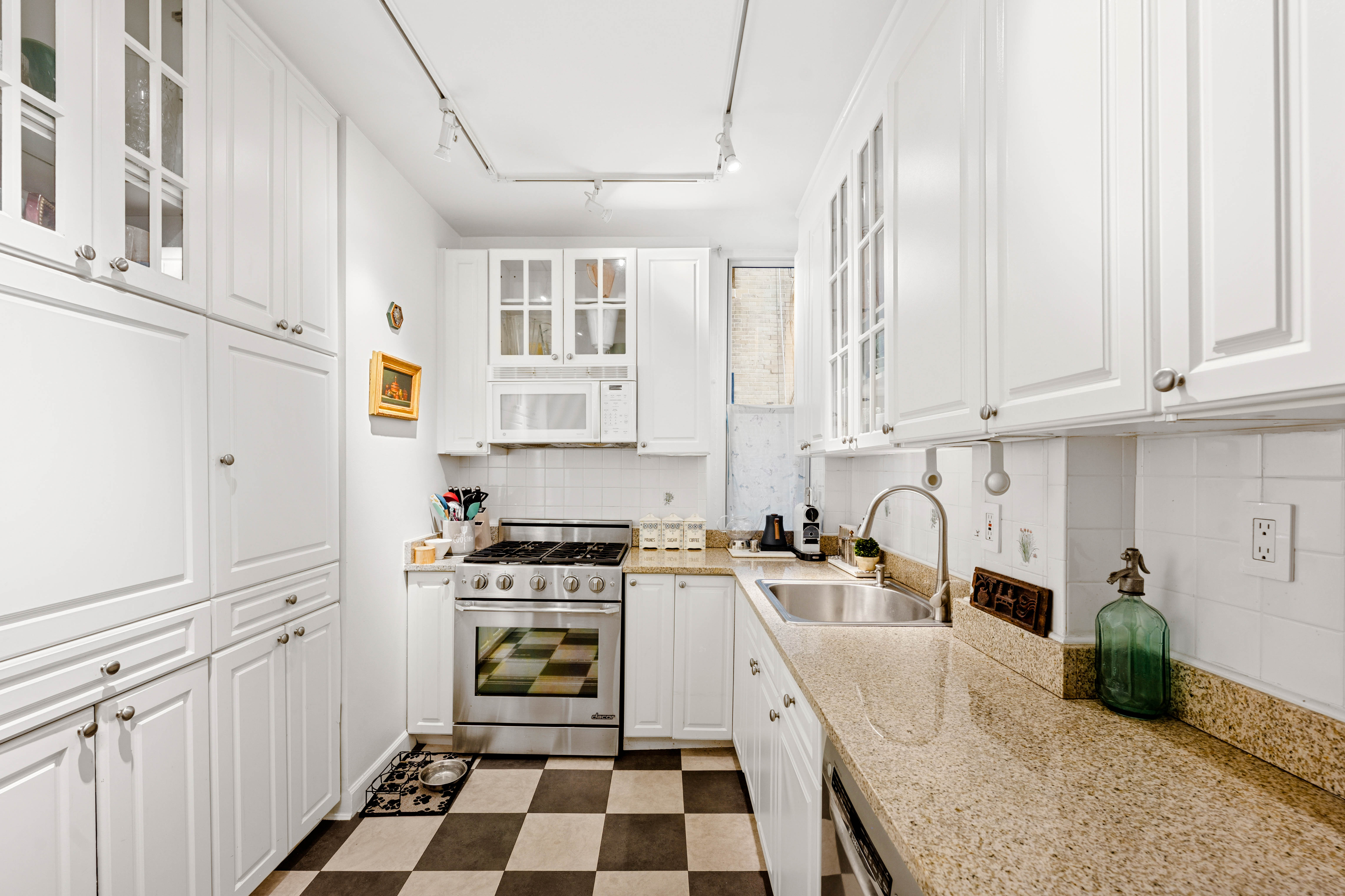 50 West 67th Street, Unit 4F Manhattan, NY 10023 - Photo 7 of 10 a kitchen with granite countertop a sink a stove and cabinets
