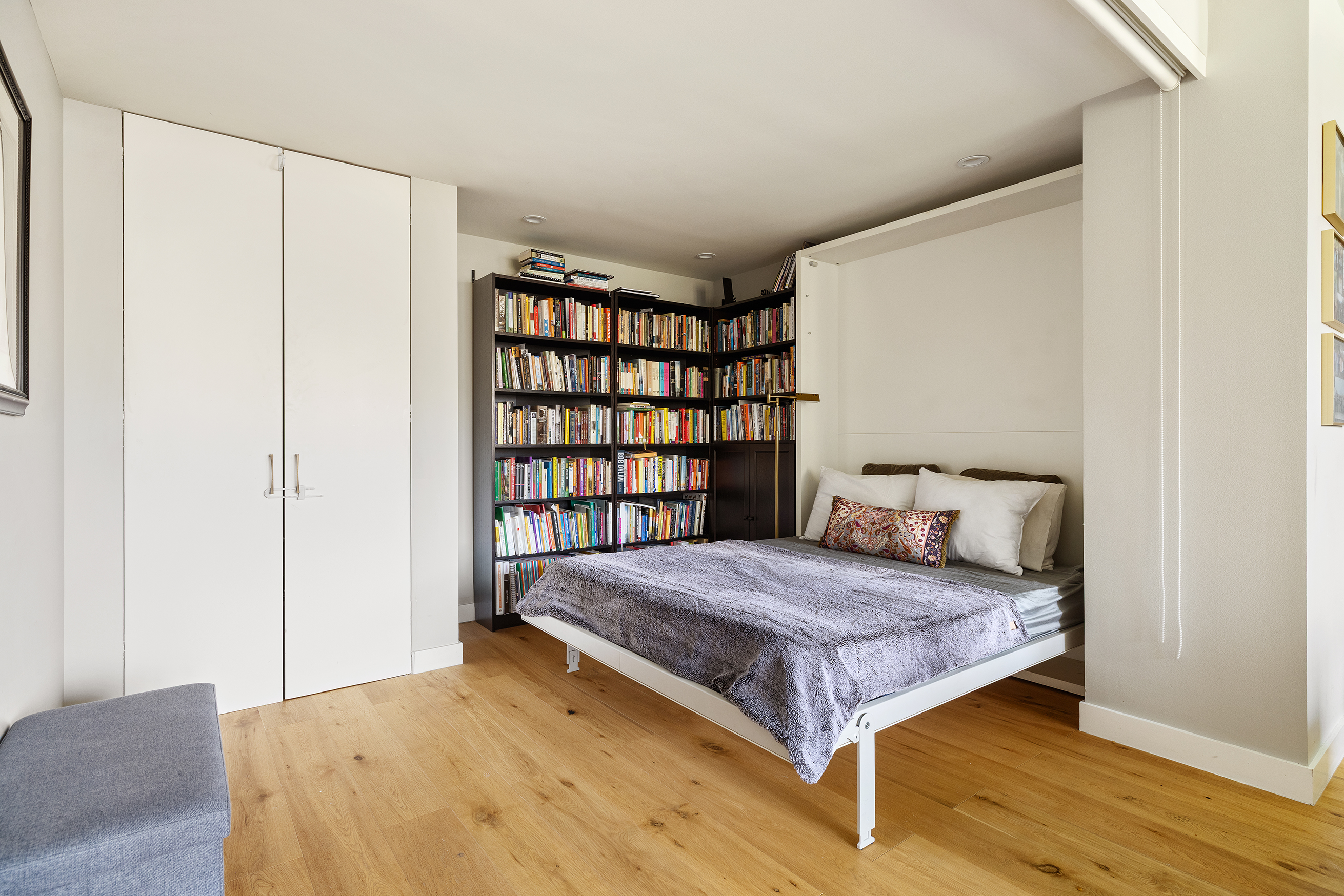 455 Main Street, Unit 4GH Manhattan, NY 10044 - Photo 8 of 9 a bedroom with a bed and a book shelf
