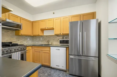 a kitchen with stainless steel appliances granite countertop a refrigerator a stove and a sink with cabinets