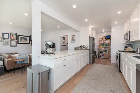 a kitchen that has a lot of cabinets in it and wooden floors