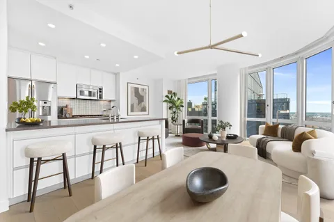 a kitchen with stainless steel appliances granite countertop a table chairs sink and cabinets