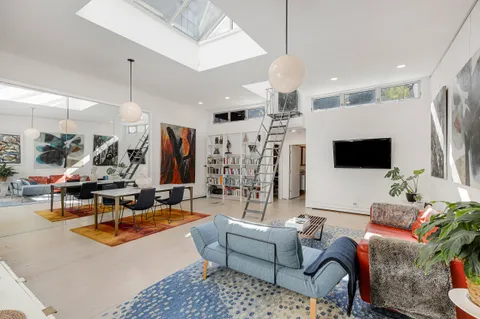 a living room with furniture kitchen view and a large window