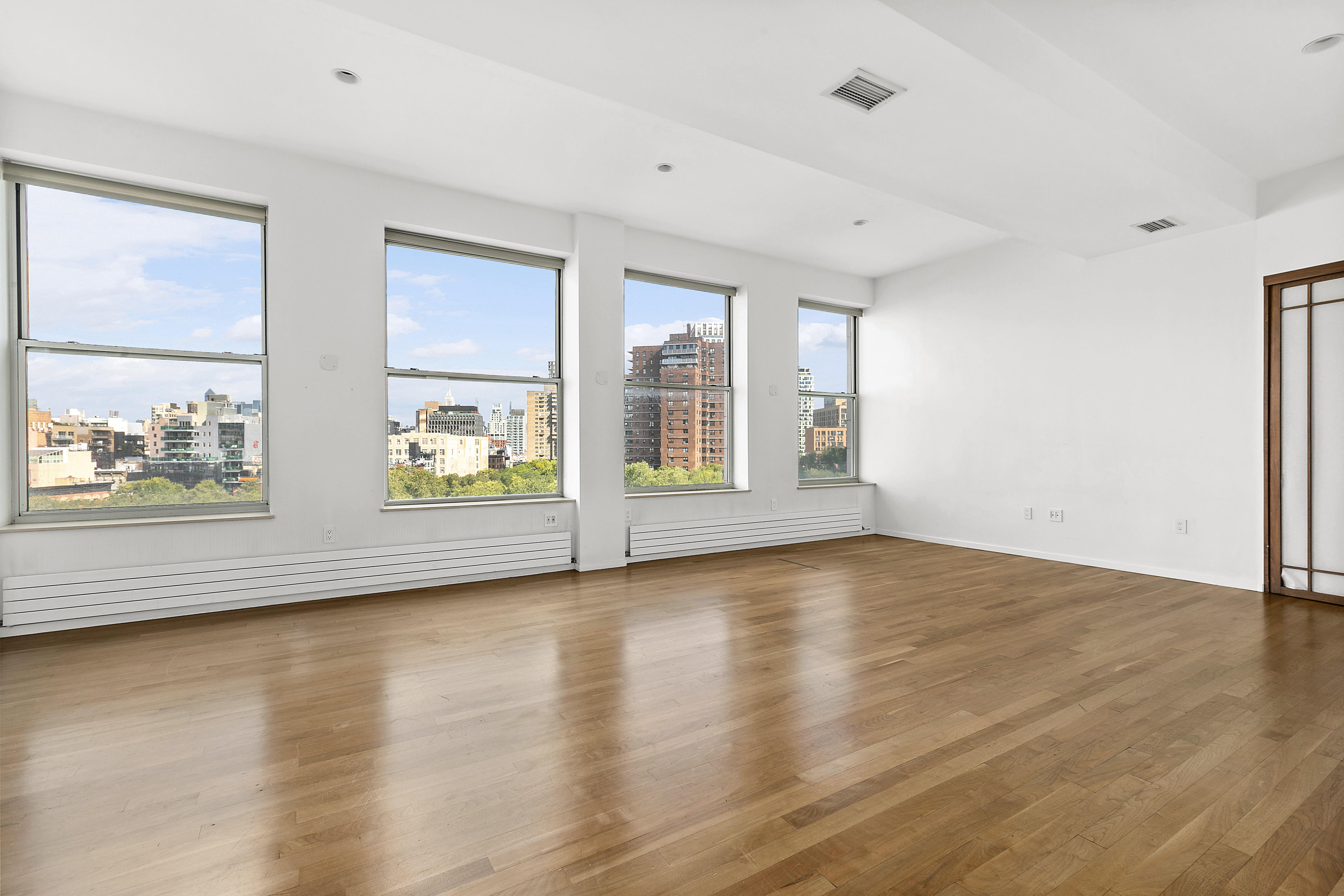 175 East Broadway, Unit 7A Manhattan, NY 10002 - Photo 2 of 9 an empty room with wooden floor and windows