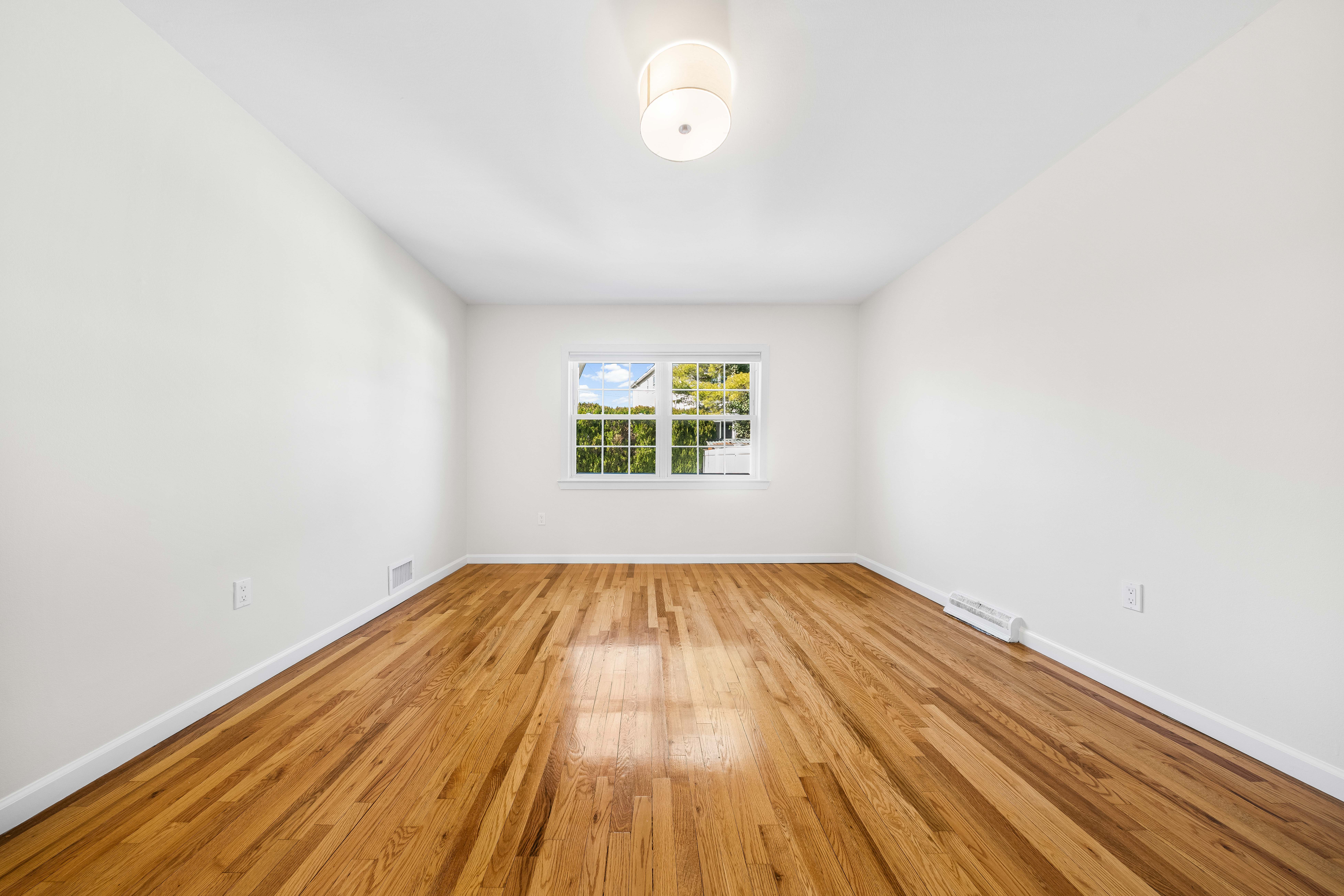 15-80 209th Street, Unit 2 Queens, NY 11360 - Photo 11 of 21 an empty room with wooden floor and windows