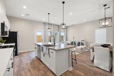 a kitchen with stainless steel appliances granite countertop a sink a stove a refrigerator and a wooden floor