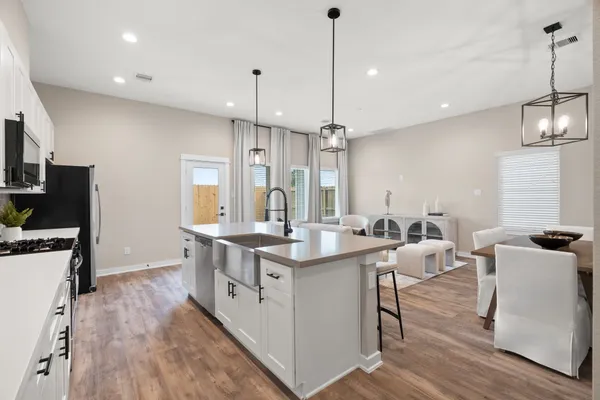 a kitchen with stainless steel appliances granite countertop a sink a stove a refrigerator and a wooden floor