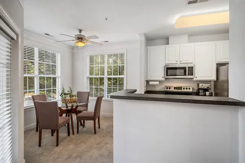 a kitchen with stainless steel appliances granite countertop a stove top oven a sink a dining table and chairs